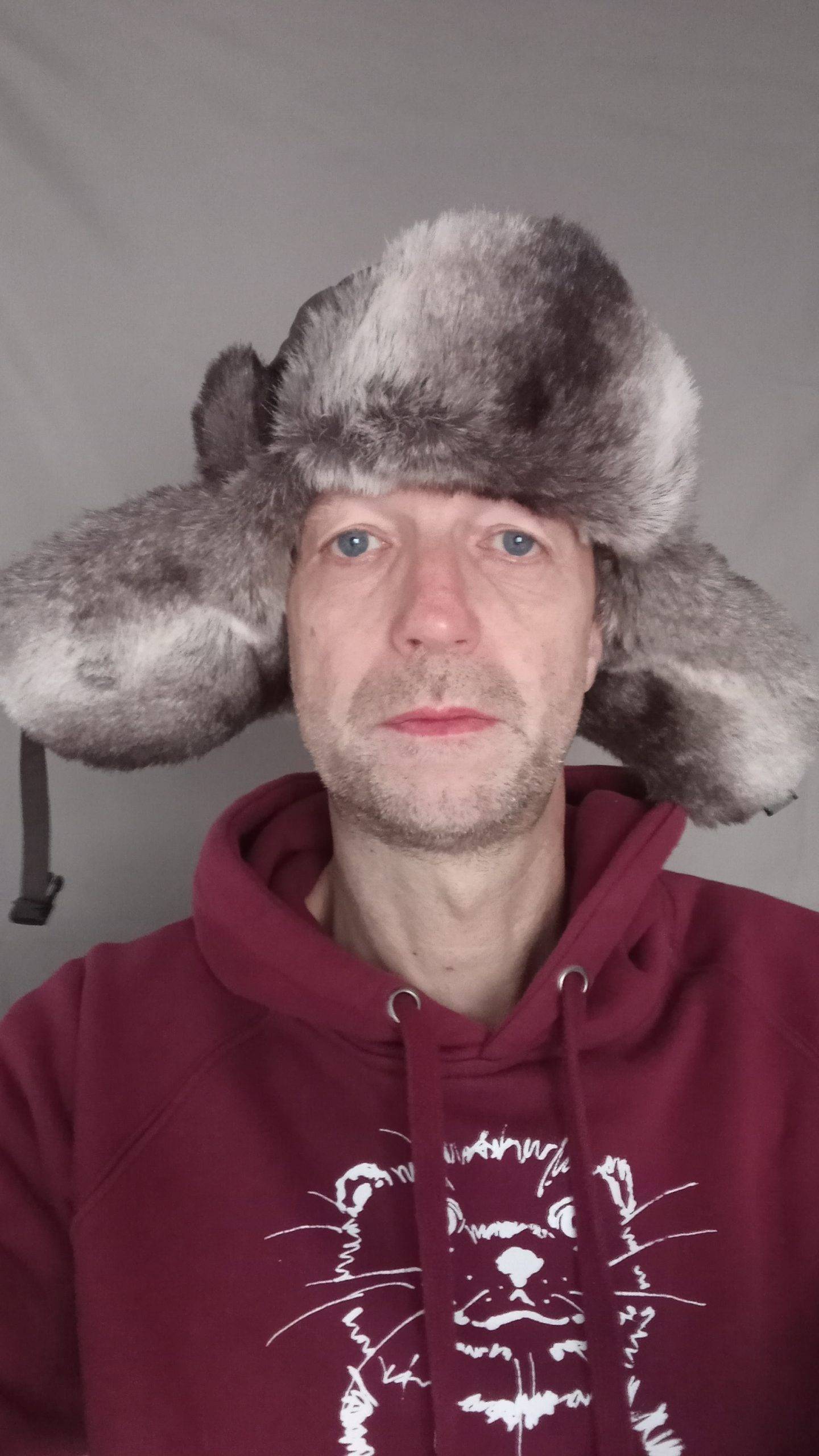 Martin mit Fellmütze und rotem Kapuzenpulli, der ein Tiermotiv hat